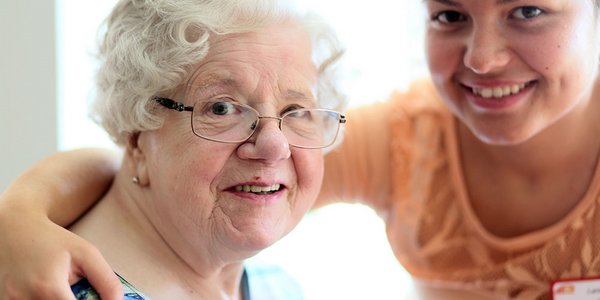 MItarbeiterin kümmert sich liebevoll um eine ältere Dame.