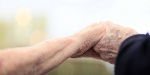 Zwei Bewohnerinnen halten einander die Hand.