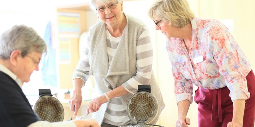 Ehrenamtliche Helferinnen backen gemeinsam Waffeln.