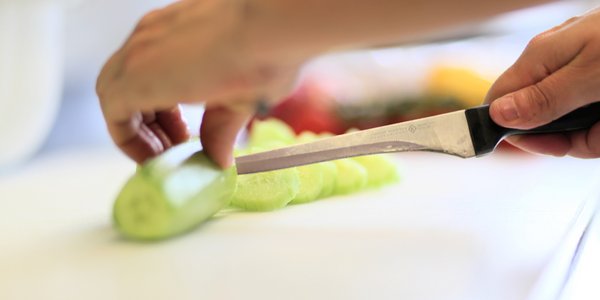 Eine Mitarbeiterin der Küche schneidet frische Gurken für die Bewohner.