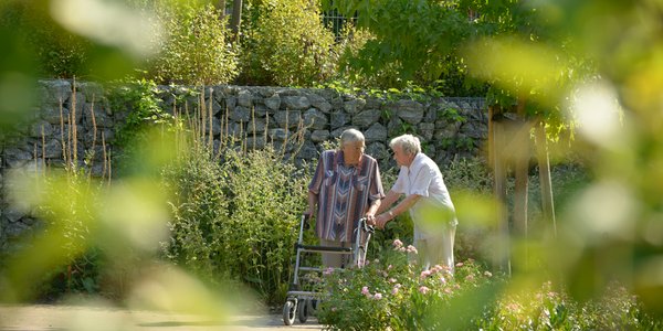 Zwei Bewohnerinnen spazieren gemeinsam durch den Park.