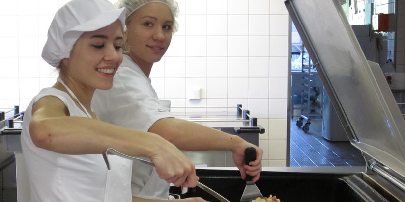 Zwei Küchenmitarbeiterinnen bei der Zubereitung.