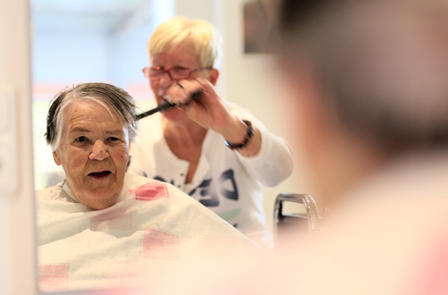 Friseurin schneidet einer älteren Dame die Haare.